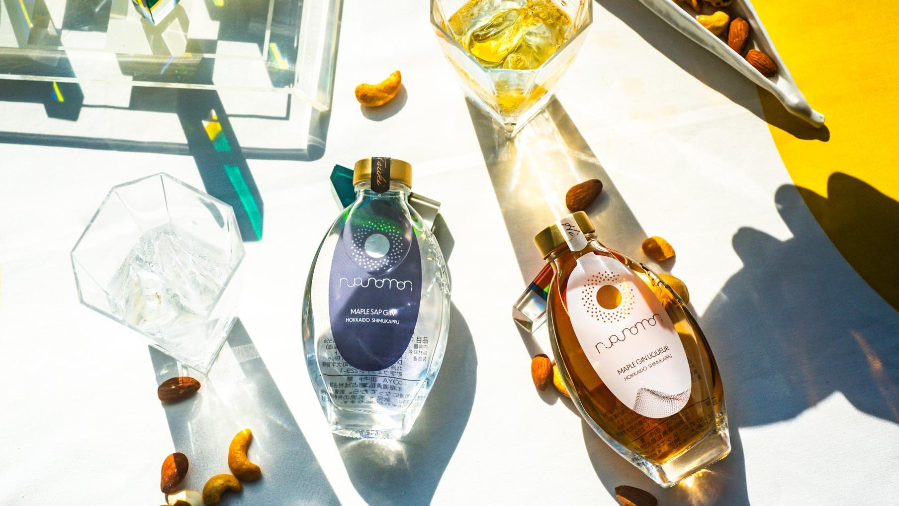 ルプノモリシリーズの北海道クラフトジン 『TSUKI』とリキュール『HI』のボトルを自然光の中で撮影したテーブルフォト
